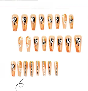Détails de faux ongles dégradés orange avec motifs yin yang, cerise et marguerite