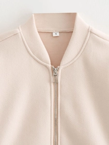 Detailed close-up of pale pink casual jacket featuring silver metal zipper and ribbed collar