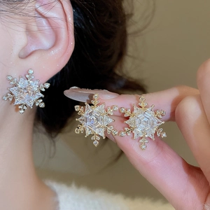 Macro detail of elegant gold snowflake stud earrings featuring sparkling cubic zirconia stones