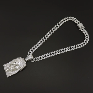 Detailed view of silver-tone iced out Cuban chain with crystal-encrusted Jesus head pendant