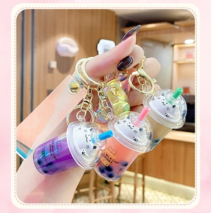 Detailed close-up of three colorful cat milk tea keychains in pink purple and brown