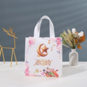 Detail of white Eid Mubarak non-woven gift bag with pink handles and golden moon graphics