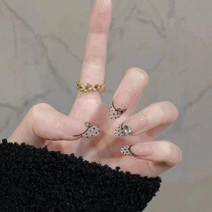 Classic nude pink press-on nails with black polka dots, bows and golden butterfly ring
