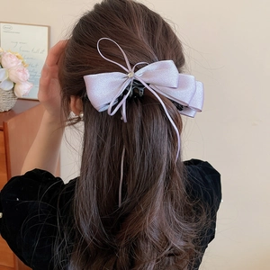 Detailed back view of a large lavender satin bow hair clip worn in a graceful hairstyle