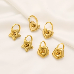 Detailed view of three pairs of gold star, heart and pentagon hoop earrings on silk