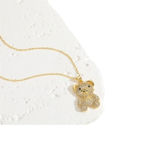 Golden bear pendant necklace with white zircons on a textured stone background