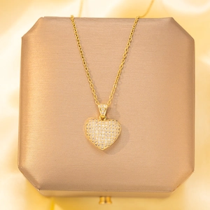 Elegant gold heart pendant necklace with shimmering pave zircons on luxury silk background