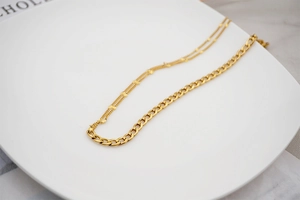 Close-up of golden layered titanium steel necklace with cuban links on marble