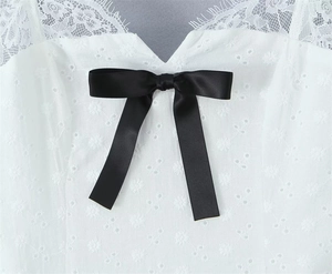 Detailed view of white lace embroidery dress featuring a delicate black ribbon bow knot