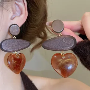 Retro resin heart drop earrings with wood details and amber marble texture on model