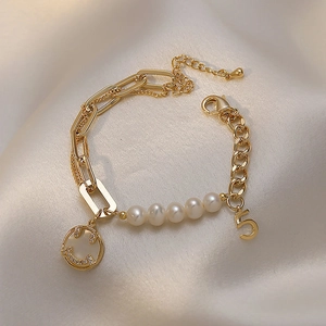 Detail of gold pearl bracelet with number five pendant and sparkling smiley face charm