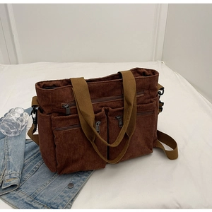 Detailed view of brown corduroy tote bag with multi-pocket zippers and adjustable strap