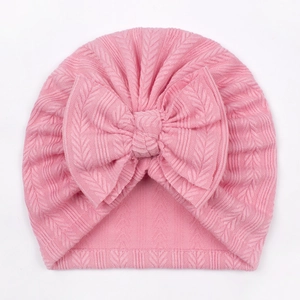 Detail of pink waffle knit baby turban hat featuring a large soft decorative bow