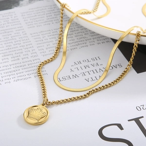 Detail of layered gold-plated necklace with crown coin pendant and snake bone chain