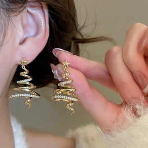 Close-up of gold-plated spiral Christmas tree earrings with sparkling zircon stars