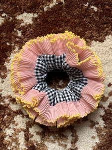 Macro view of oversized pink and gingham scrunchie with yellow wavy edge stitching