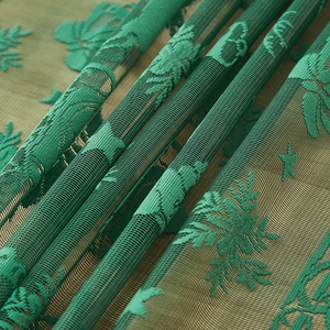 Detail der waldgrünen Weihnachtsspitze-Tischdecke mit Blumen- und Sternenstickereien