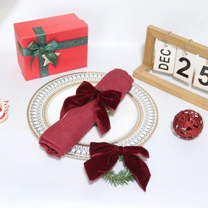 Close-up of burgundy velvet bow napkin ring with pine needles on Christmas table setting
