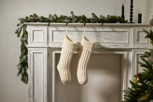 Close-up of cream white cable knit Christmas stockings hanging on a vintage fireplace mantel
