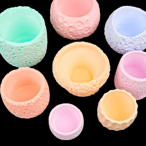 Macaron pastel colored succulent pots with lunar crater texture on black background