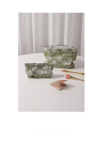 Close-up of floral embroidered cotton linen makeup bags in green with white hydrangeas