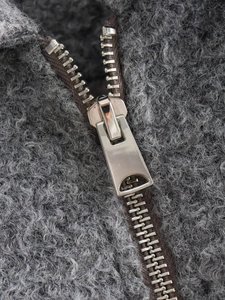 Macro shot of silver metal zipper on dark gray textured sherpa fleece jacket fabric