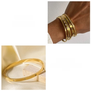 Dettaglio di bracciali in acciaio al titanio dorato con motivi a stella e inserti in zircone
