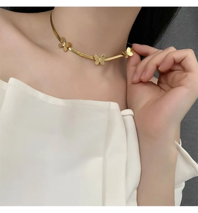 Détail de trois breloques papillon dorées sur un collier à chaîne serpent lisse