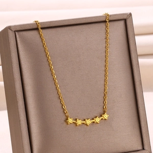 Détail macro du collier doré avec cinq étoiles texturées sur une chaîne à maillons
