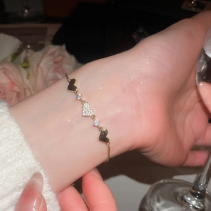 Detailed view of gold-plated heart bracelet with zircon stones on a female wrist