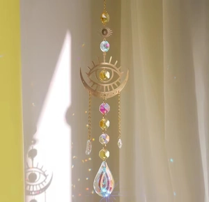 Detail of crystal suncatcher moon pendant with prism reflecting rainbow light on curtain