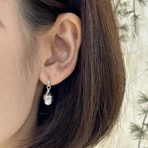 Detail of 925 silver bell earring with round pearl on ear showing polished finish