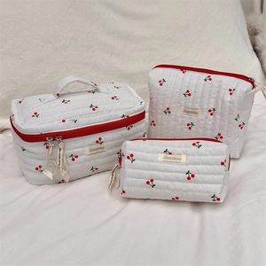 Detailed macro view of quilted cotton fabric texture with red cherry print on toiletry bags