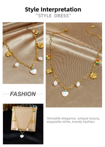 Close-up of golden necklace with strawberry, pearl and flower charms on silk