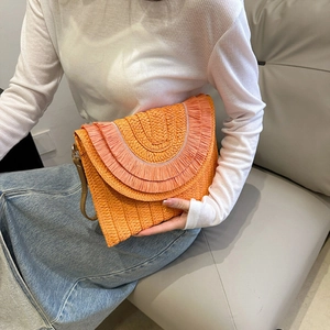 Detail showing the orange raffia woven envelope bag with tiered fringe and long strap