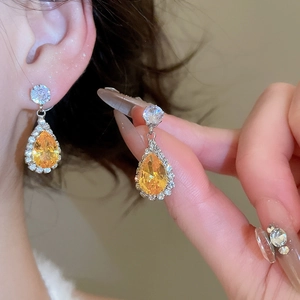 Close-up of elegant silver drop earrings with large yellow teardrop zircon stones
