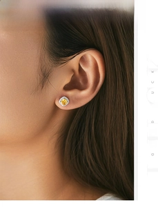 Detailed view of square yellow crystal stud earrings worn by a model in soft light