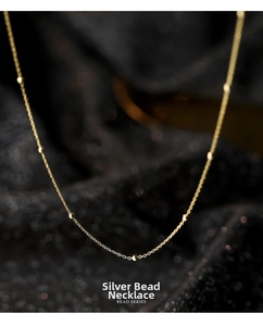 Detailed close-up of S925 sterling silver gold beaded necklace on a dark background