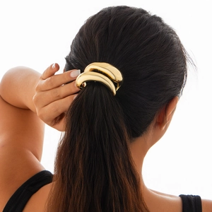 Elegant gold metal arched ponytail clip hair accessory shown on model's hair