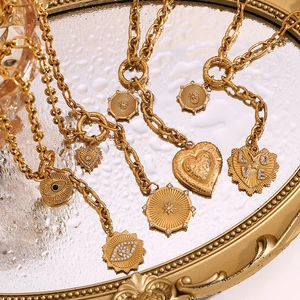 Macro shot of 18K gold plated heart and eye pendants on a vintage mirror surface