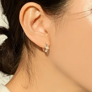 Close-up of minimalist silver hoop earrings with pearl inlay worn by a model
