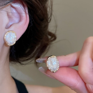 Close-up of irregular pearl earrings with gold wave edges showing exquisite texture