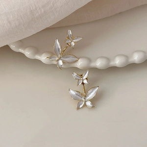 Elegant gold butterfly earrings with pearlescent wings on decorative ceramic tray