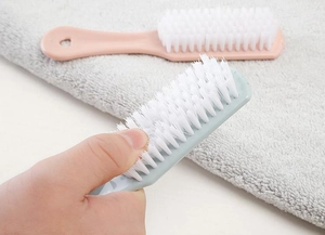 Dettaglio delle setole bianche flessibili e del manico in plastica della spazzola per scarpe