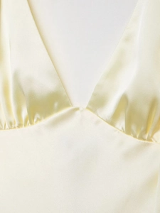 Macro detail of champagne satin midi dress featuring a V-neckline and elegant pleats