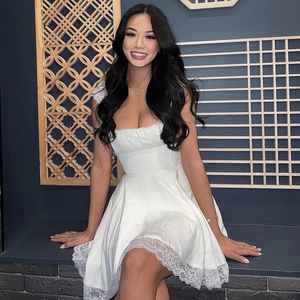 Close-up of a white strapless mini dress featuring delicate lace trim hem and chic cutout