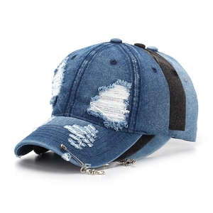 Detail of distressed denim baseball caps with vintage cross charms and safety pin accents