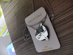 Detail view of two 316L stainless steel heart puzzle pendants with custom letter engraving