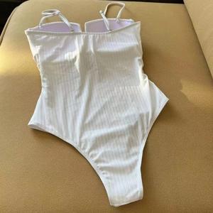 Detail of white ribbed one-piece swimsuit with spaghetti straps and low back design