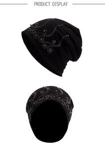 Detail of black slouchy beanie featuring elegant silver bead scroll pattern embroidery